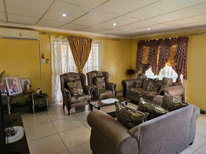 Spacious living room featuring tiled flooring, a split-system air conditioner, and direct access to the garden through a glass panel door.