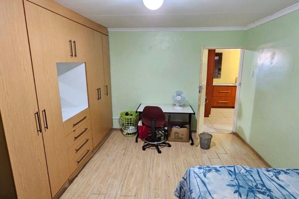 A bedroom featuring light wood-look laminate flooring and a large built-in wardrobe with integrated shelving.
