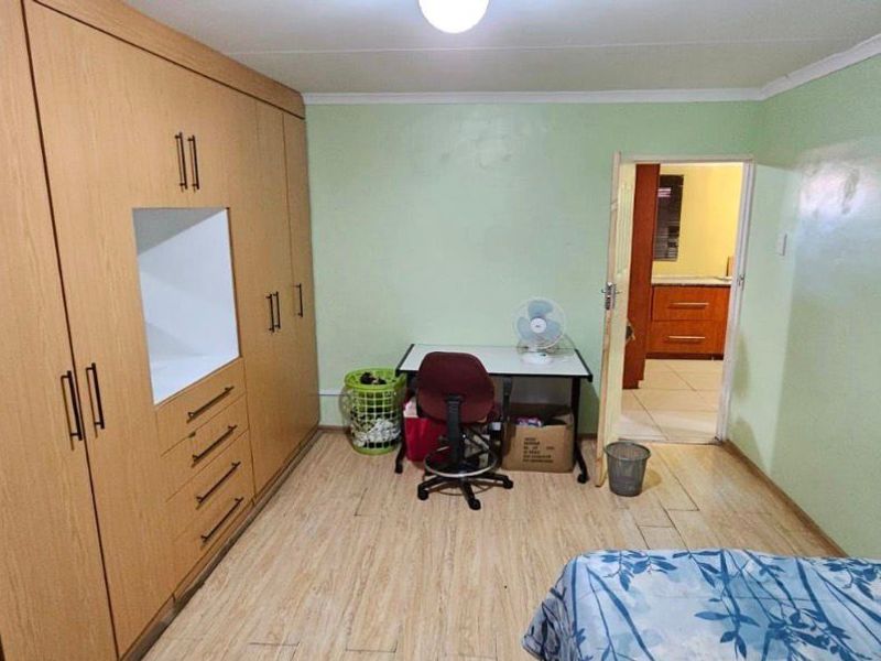 A bedroom featuring light wood-look laminate flooring and a large built-in wardrobe with integrated shelving.