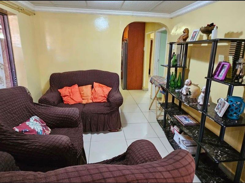 A living room featuring tiled flooring, a decorative pillar, and an arched entryway leading to the rest of the home.