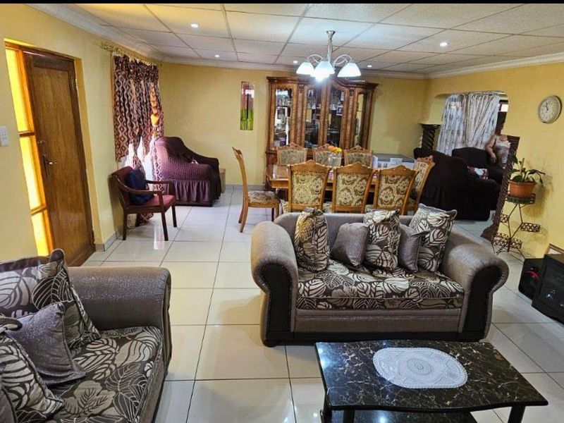 Spacious open-plan living and dining area featuring tiled flooring, a drop ceiling with recessed lighting, and neutral wall finishes.