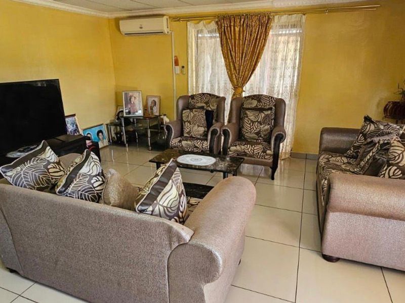 A living room featuring tiled flooring, a wall-mounted air conditioning unit, and decorative cornice detailing.