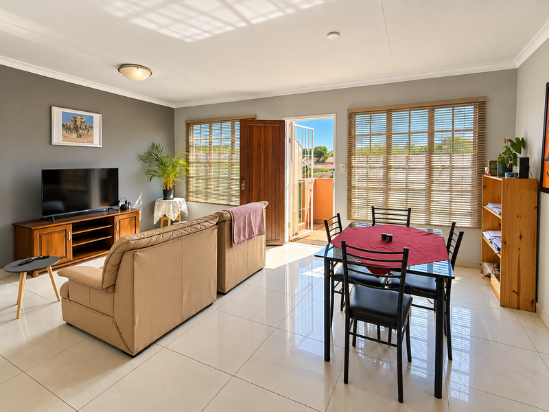 Bright open-plan living and dining area featuring large format floor tiles, neutral wall tones, and direct access to an outdoor balcony.