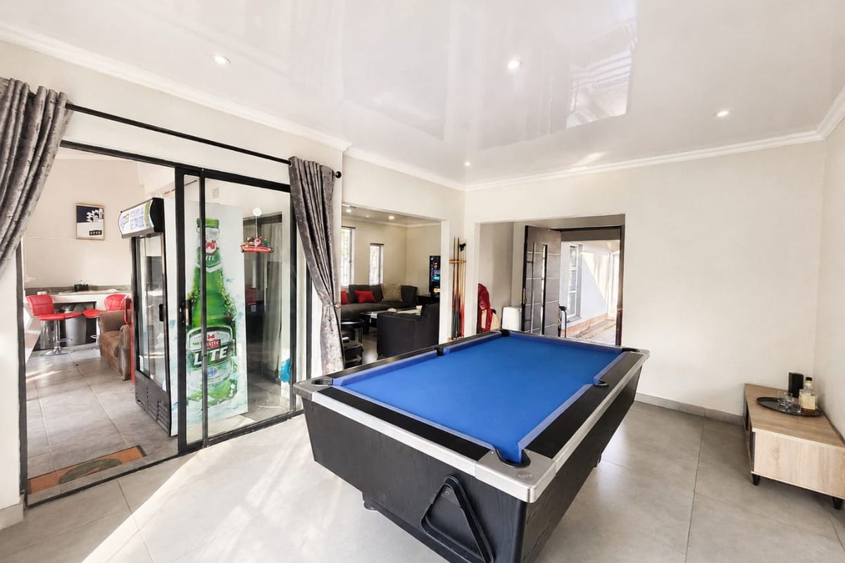 Spacious living area featuring glossy stretch ceilings, tiled flooring, and large sliding glass doors providing access to an adjacent entertainment space.