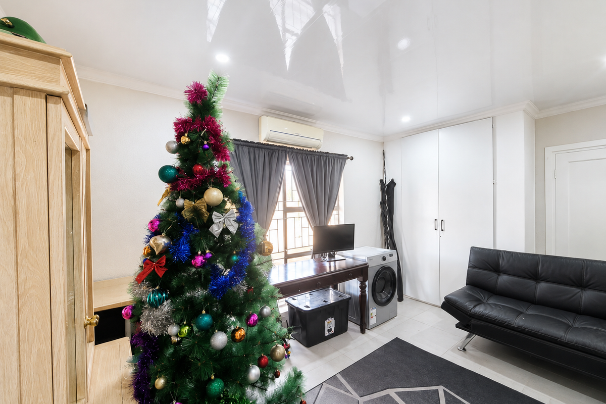 A bedroom featuring a glossy ceiling, built-in wardrobe, and split-system air conditioning unit, providing a functional and well-maintained living space.
