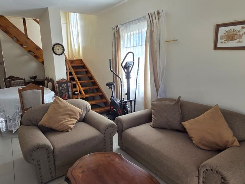 Open plan living and dining area featuring tiled flooring and a wooden staircase leading to the upper level.