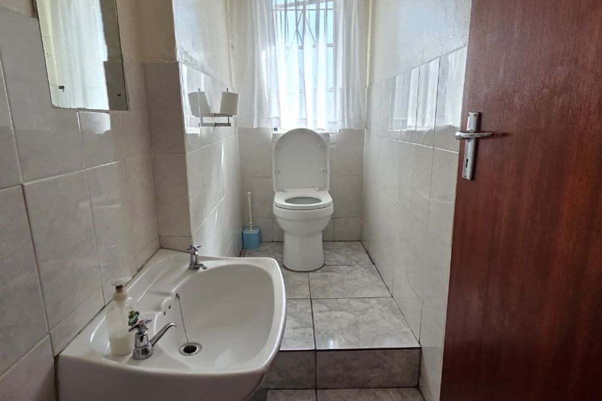 A functional bathroom featuring a pedestal basin, toilet, and tiled finishes throughout, providing a clean and practical space.