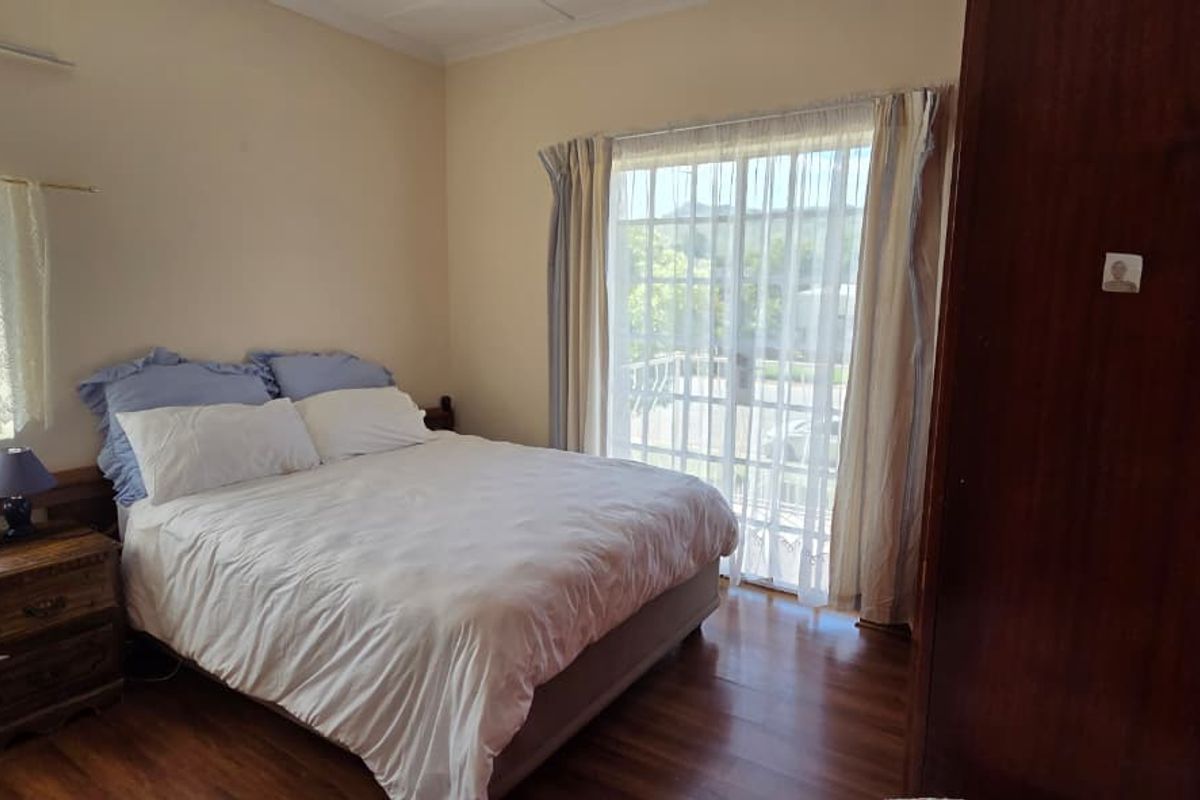 A bedroom featuring laminate flooring, a built-in wardrobe, and a sliding glass door providing natural light and access to the exterior.