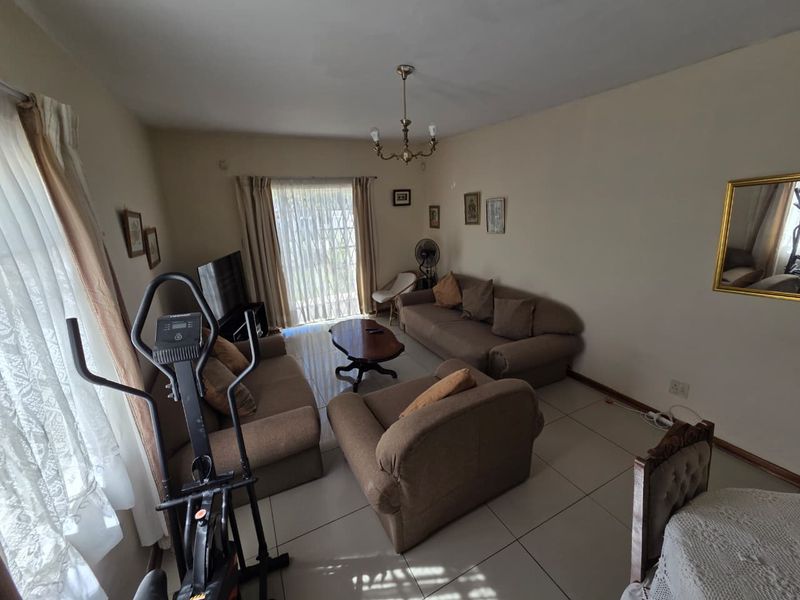 A spacious living room featuring tiled flooring and a sliding glass door that provides natural light and access to the exterior.