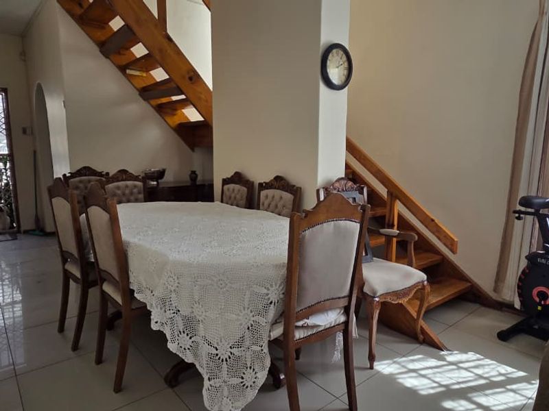 Dining area featuring tiled flooring and an open wooden staircase leading to the upper level, with access to a secure exterior door.