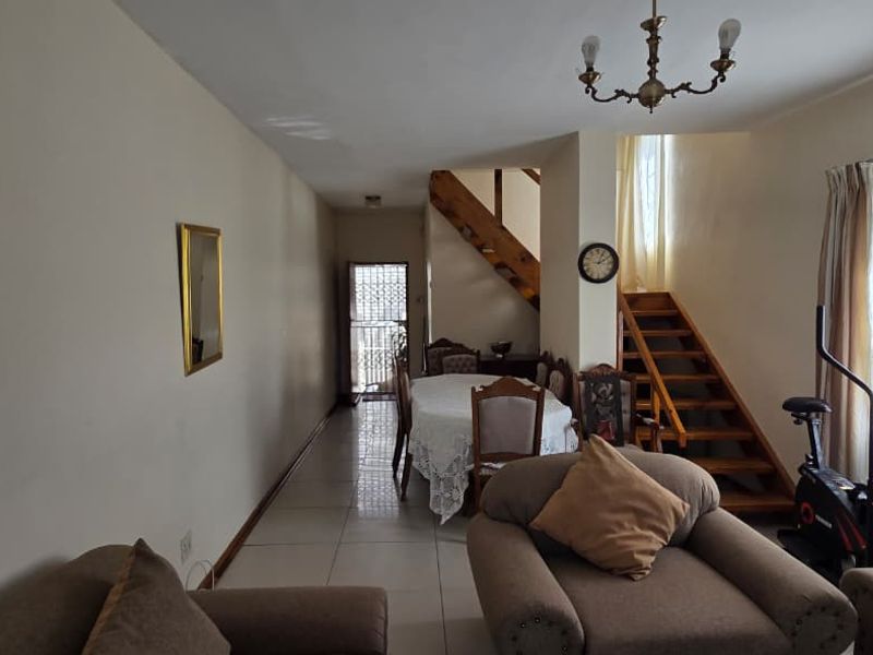Open plan living and dining area featuring tiled flooring and a wooden staircase leading to the upper level.