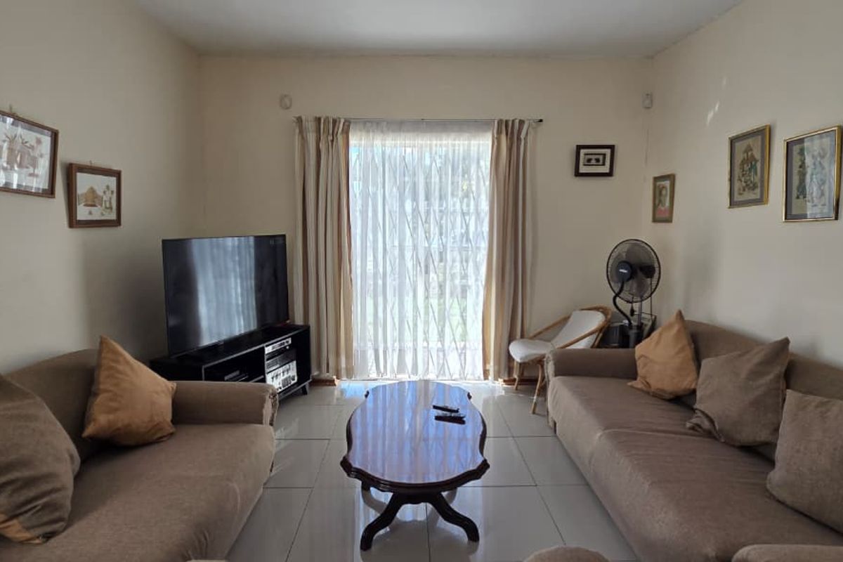 A comfortable living room featuring tiled flooring and a large sliding glass door that provides natural light and access to the outdoors.