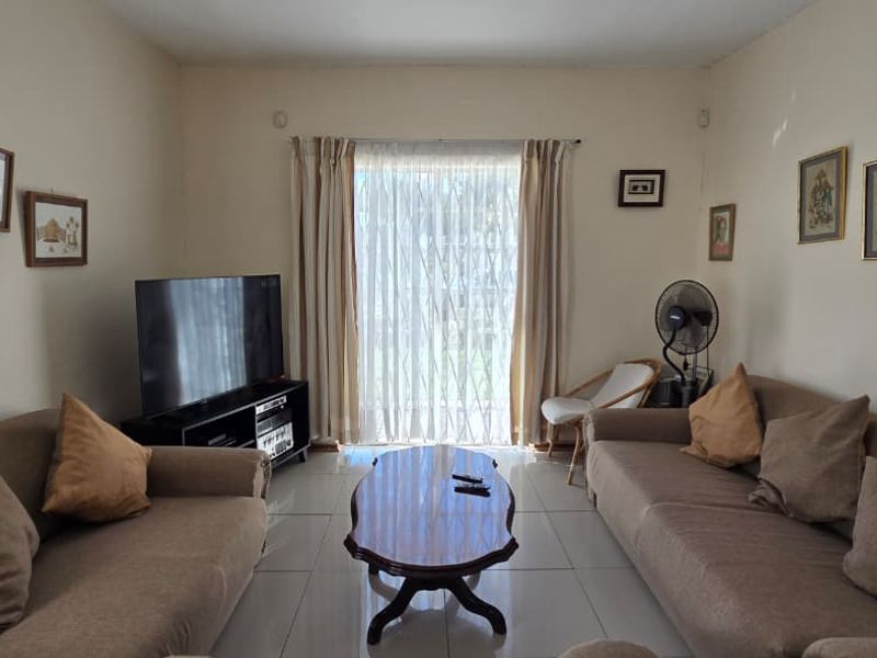 A comfortable living room featuring tiled flooring and a large sliding glass door that provides natural light and access to the outdoors.