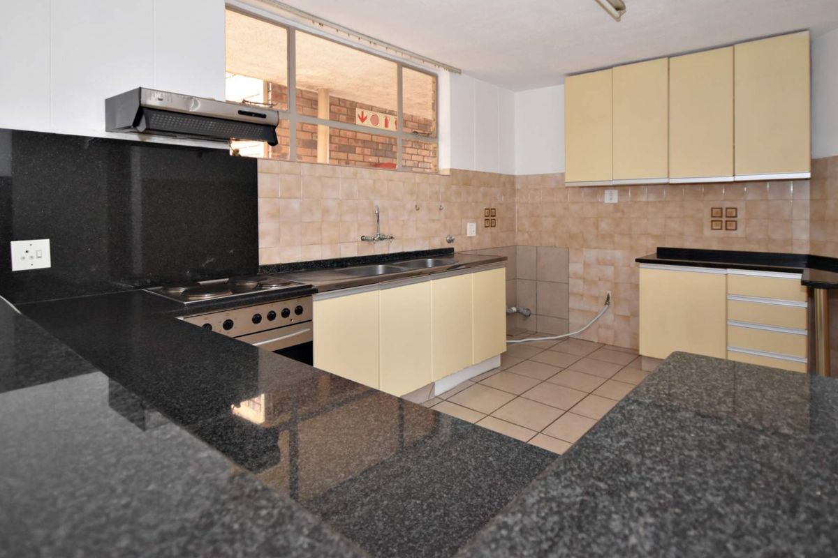A functional kitchen featuring granite countertops, built-in oven, extractor fan, and ample cabinetry, offering a clean space ready for modern updates.