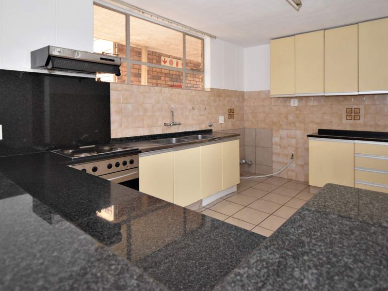 A functional kitchen featuring granite countertops, built-in oven, extractor fan, and ample cabinetry, offering a clean space ready for modern updates.