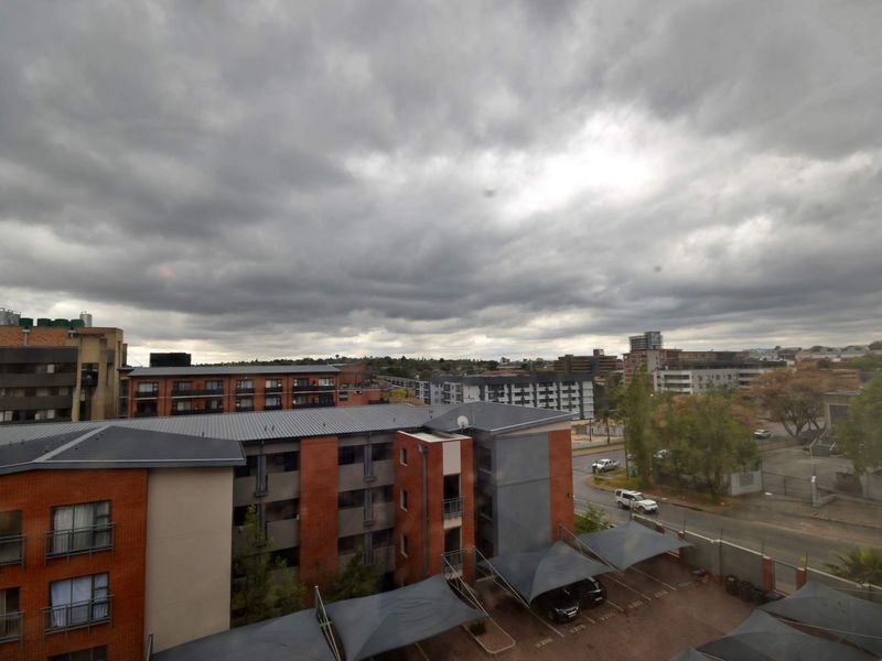 An elevated view overlooking the apartment complex, featuring brick building facades, metal roofing, and covered parking bays.