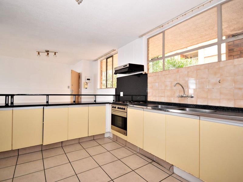 A functional kitchen featuring built-in cabinetry, a stainless steel sink, an integrated oven with extractor fan, and a breakfast bar counter.