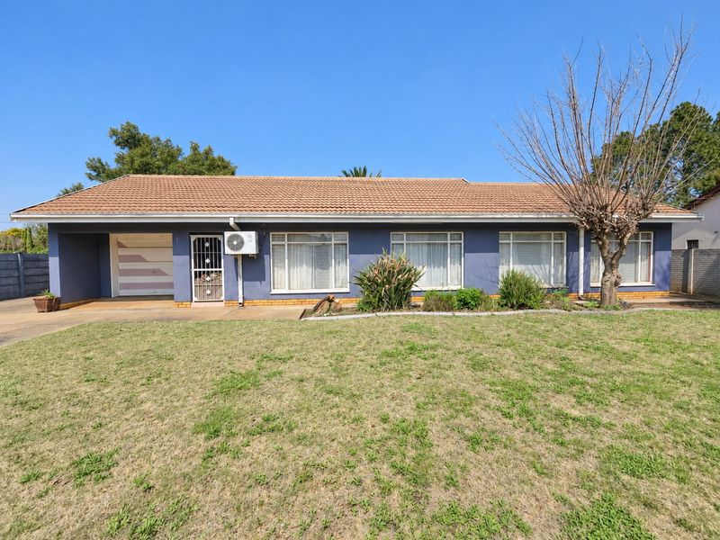 Front elevation of a single-story house featuring a tiled roof, integrated garage, and large windows, set on a spacious lawn.