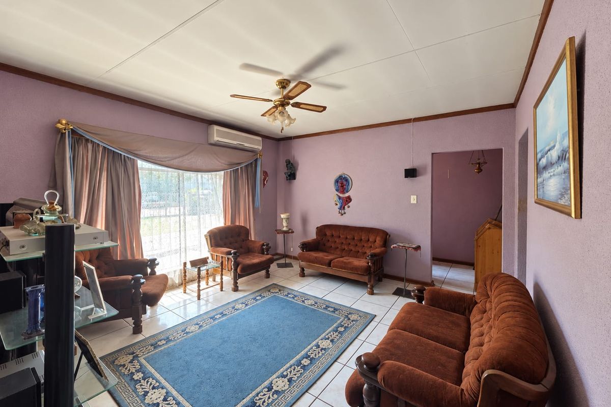 A living room featuring tiled flooring, a ceiling fan, and a split-system air conditioner, with access to the exterior via a sliding glass door.