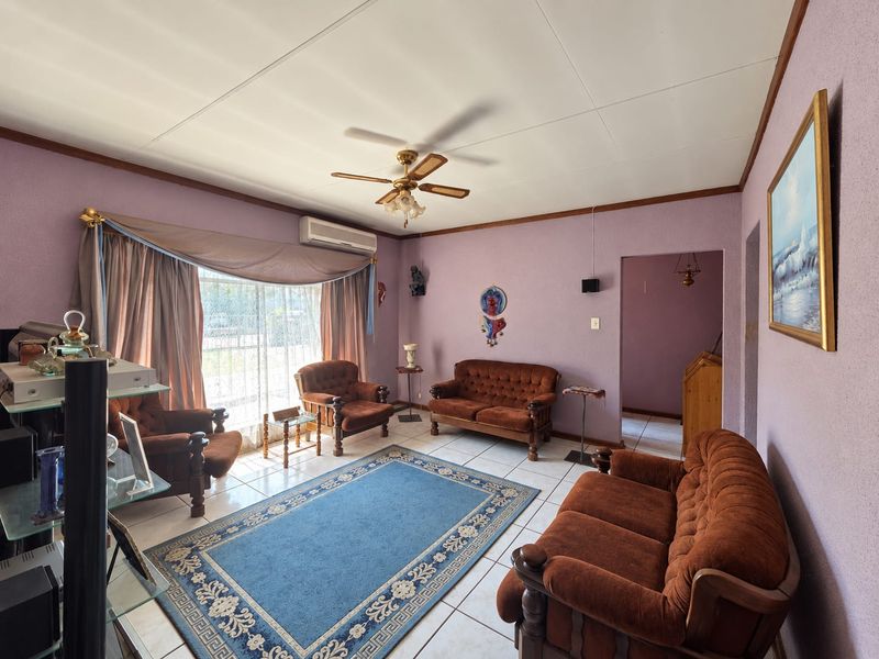 A living room featuring tiled flooring, a ceiling fan, and a split-system air conditioner, with access to the exterior via a sliding glass door.