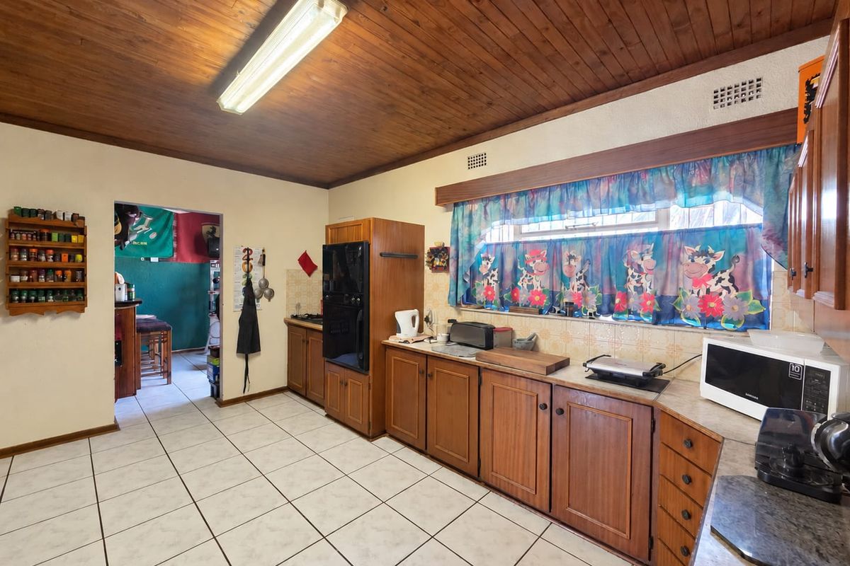 A dated kitchen featuring wooden cabinetry, tiled flooring, and a wooden ceiling, offering a functional layout with potential for modern renovation.