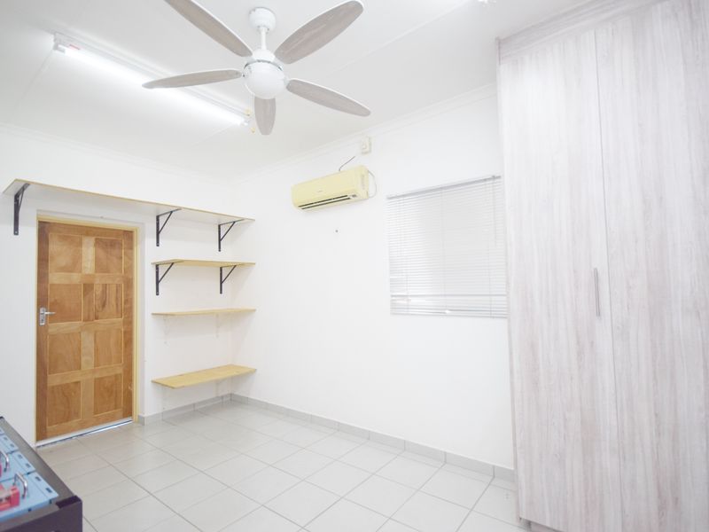 A bright, empty bedroom featuring tiled floors, a built-in wardrobe, wall-mounted shelving, a ceiling fan, and a split-system air conditioner.