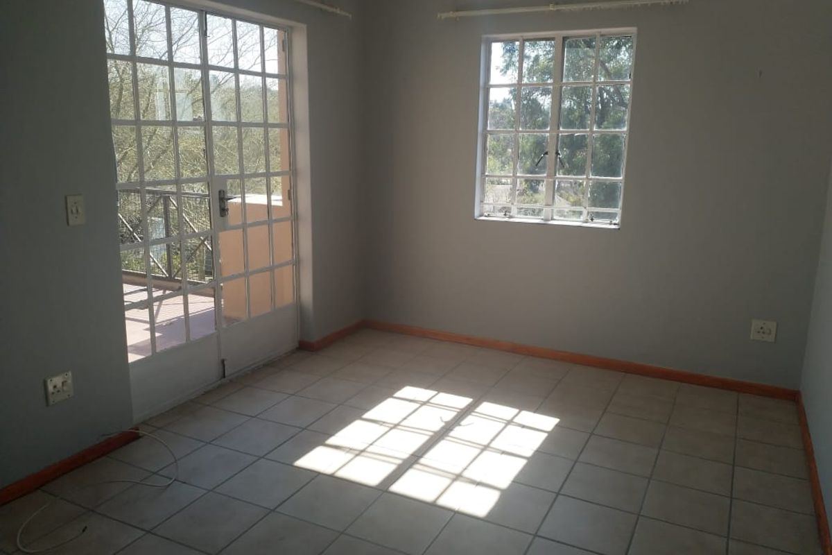 An empty bedroom featuring tiled flooring, grid-pattern windows, and glass-paneled french doors leading to an outdoor area.