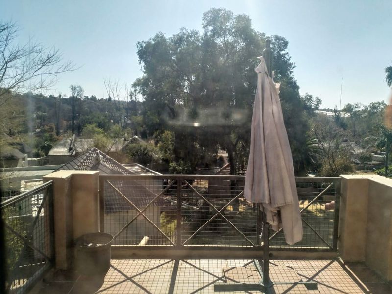 A balcony featuring tiled flooring, a metal mesh railing, and a masonry balustrade, offering an elevated view of the surrounding neighborhood.