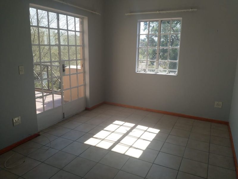 An empty bedroom featuring tiled flooring, grid-pattern windows, and glass-paneled french doors leading to an outdoor area.