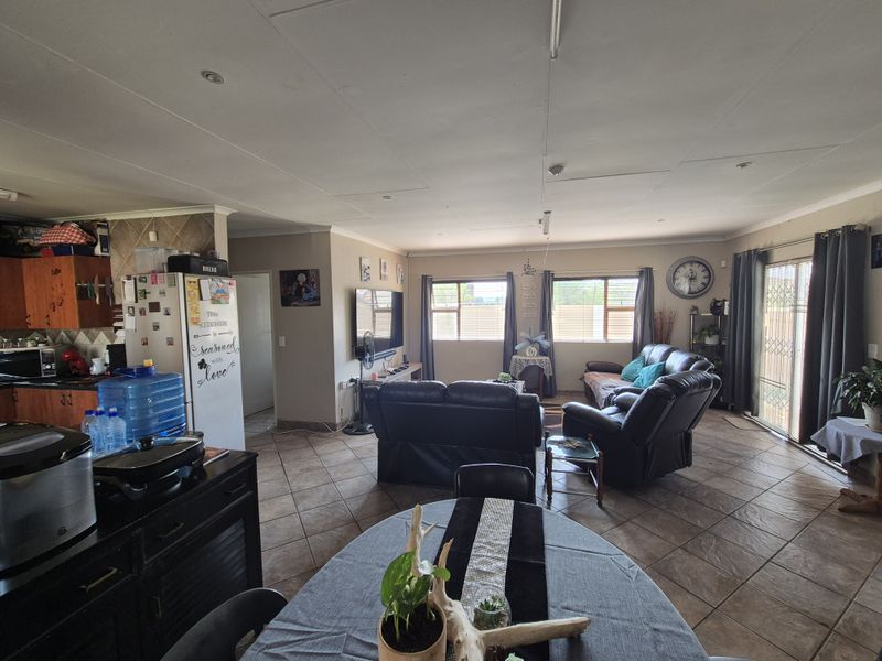 Spacious open-plan living area featuring tiled flooring, integrated kitchen cabinetry, and direct access to the outdoor area through sliding glass doors.