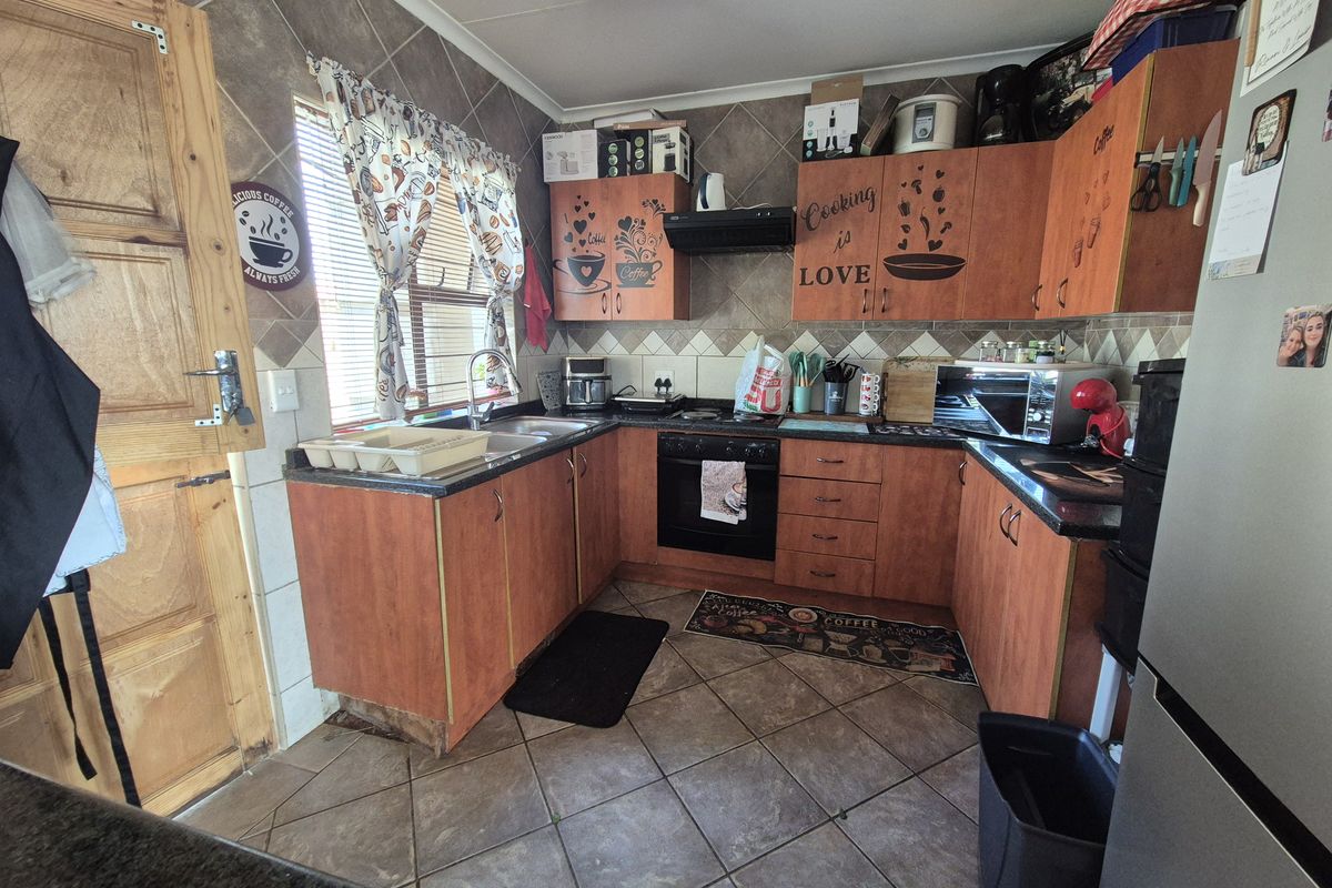 A functional kitchen featuring laminate cabinetry, granite countertops, built-in oven, extractor fan, and tiled flooring with a tiled backsplash.
