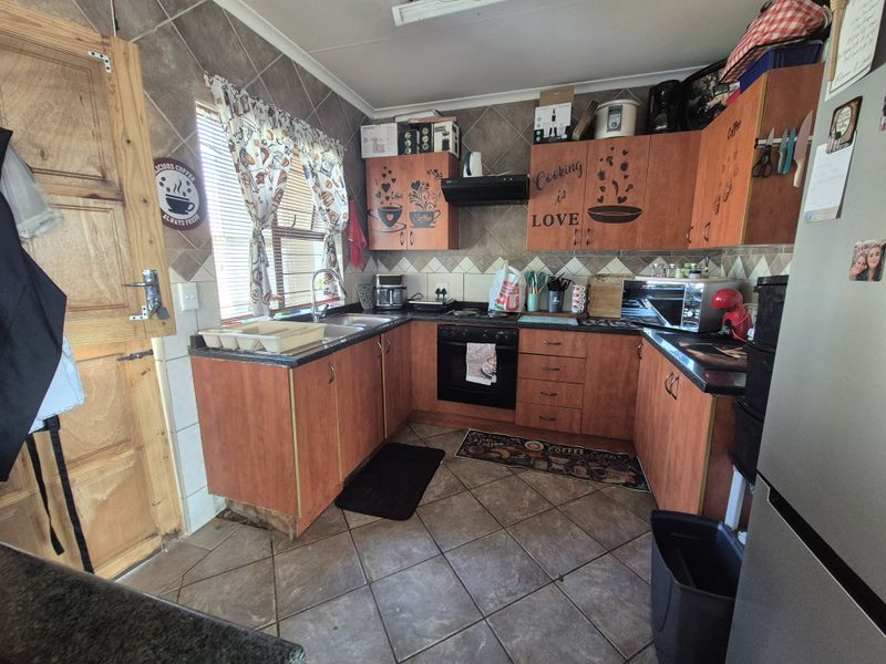 A functional kitchen featuring laminate cabinetry, granite countertops, built-in oven, extractor fan, and tiled flooring with a tiled backsplash.