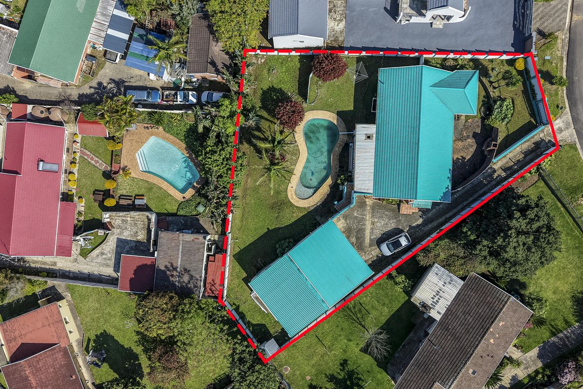 Aerial view of the property showing the main dwelling, detached garage, swimming pool, and surrounding garden area within the highlighted boundary.