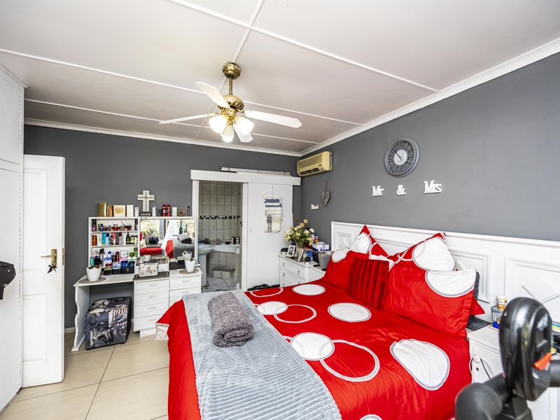 A bedroom featuring tiled flooring, a ceiling fan, split-system air conditioning, and an en-suite bathroom with built-in wardrobe storage.