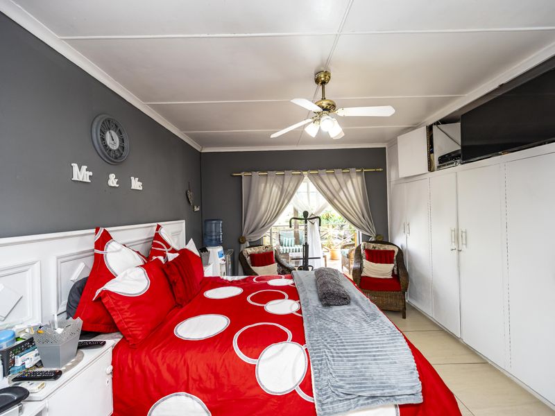 A bedroom featuring built-in cupboards, a ceiling fan, and tiled flooring, with direct access to an outdoor patio area.