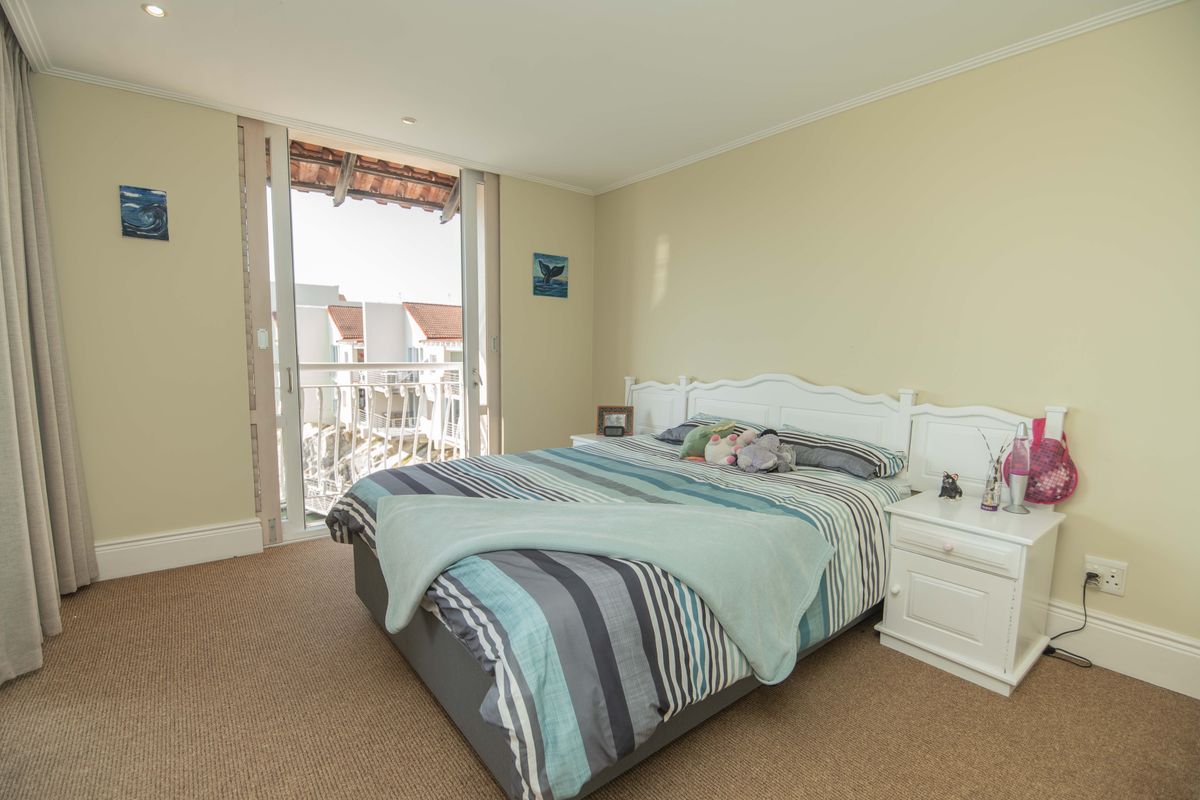 A well-lit bedroom featuring carpet flooring, recessed lighting, and a sliding glass door providing access to a private balcony.