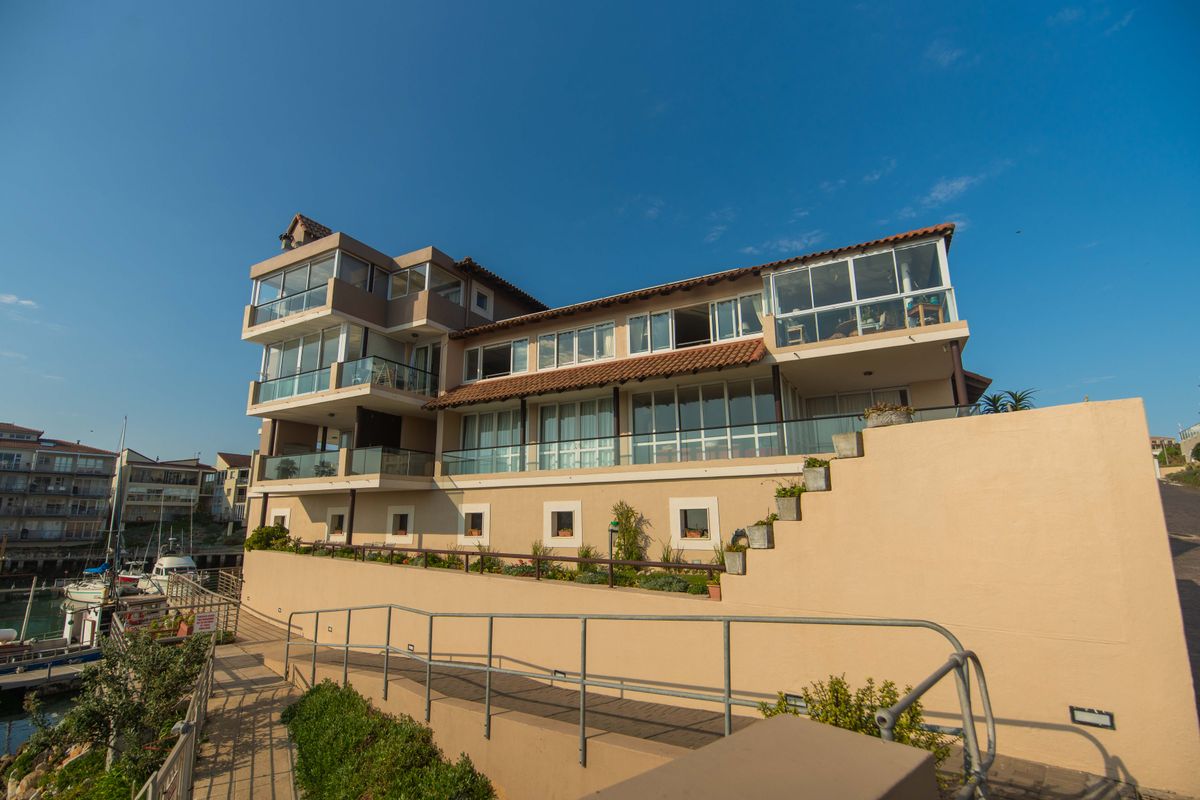 Rear elevation of a multi-story apartment building featuring tiered balconies, glass balustrades, and a landscaped terrace overlooking the marina.