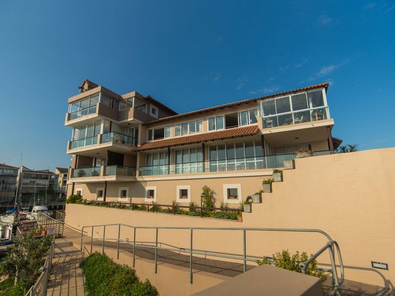 Rear elevation of a multi-story apartment building featuring tiered balconies, glass balustrades, and a landscaped terrace overlooking the marina.