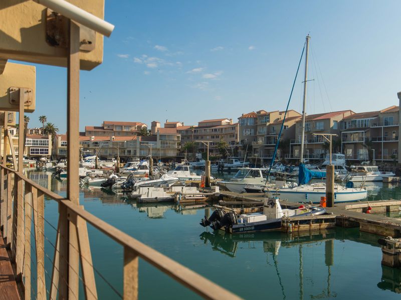 A scenic view overlooking a marina with multiple boats moored at the docks, captured from an elevated balcony.