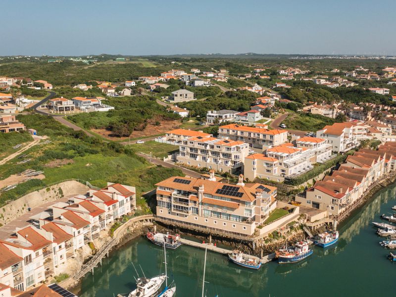Aerial view of a coastal apartment complex situated along a marina with private jetty access and solar panel installations.