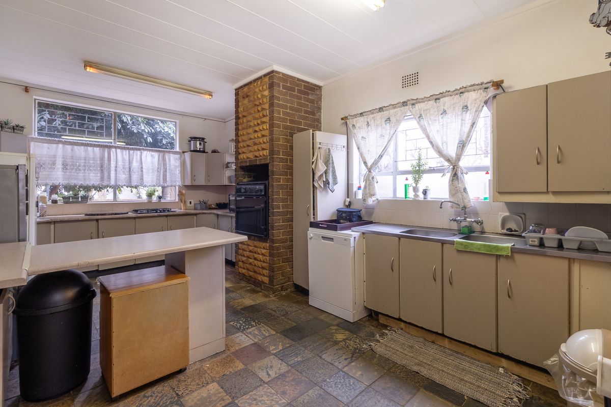 A functional kitchen featuring built-in cabinetry, a double sink, and a distinctive brick chimney breast, offering potential for a modern renovation.