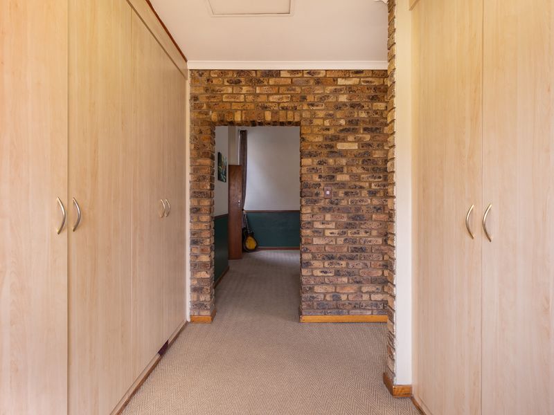 A hallway featuring extensive built-in wooden cupboards and a distinctive exposed brick archway leading to an adjacent room.