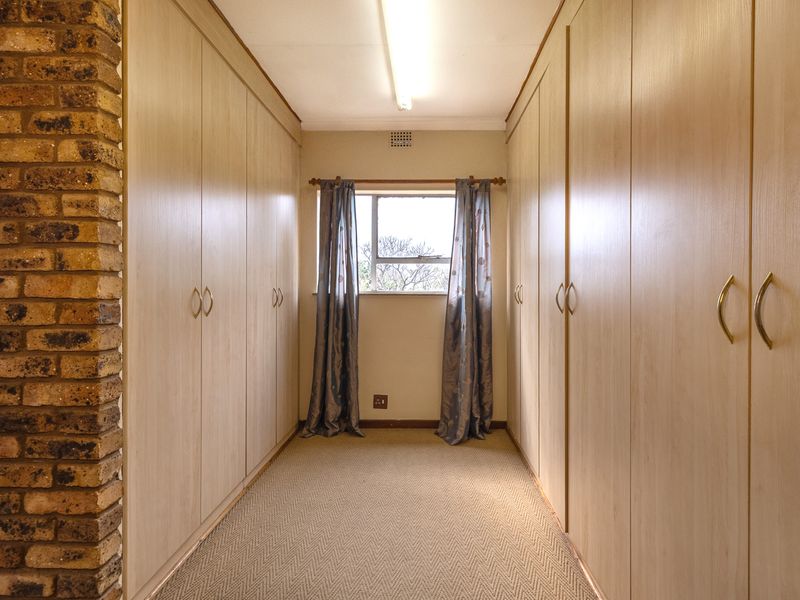 A functional hallway featuring extensive built-in cabinetry for storage, an exposed brick accent pillar, and neutral carpeting.