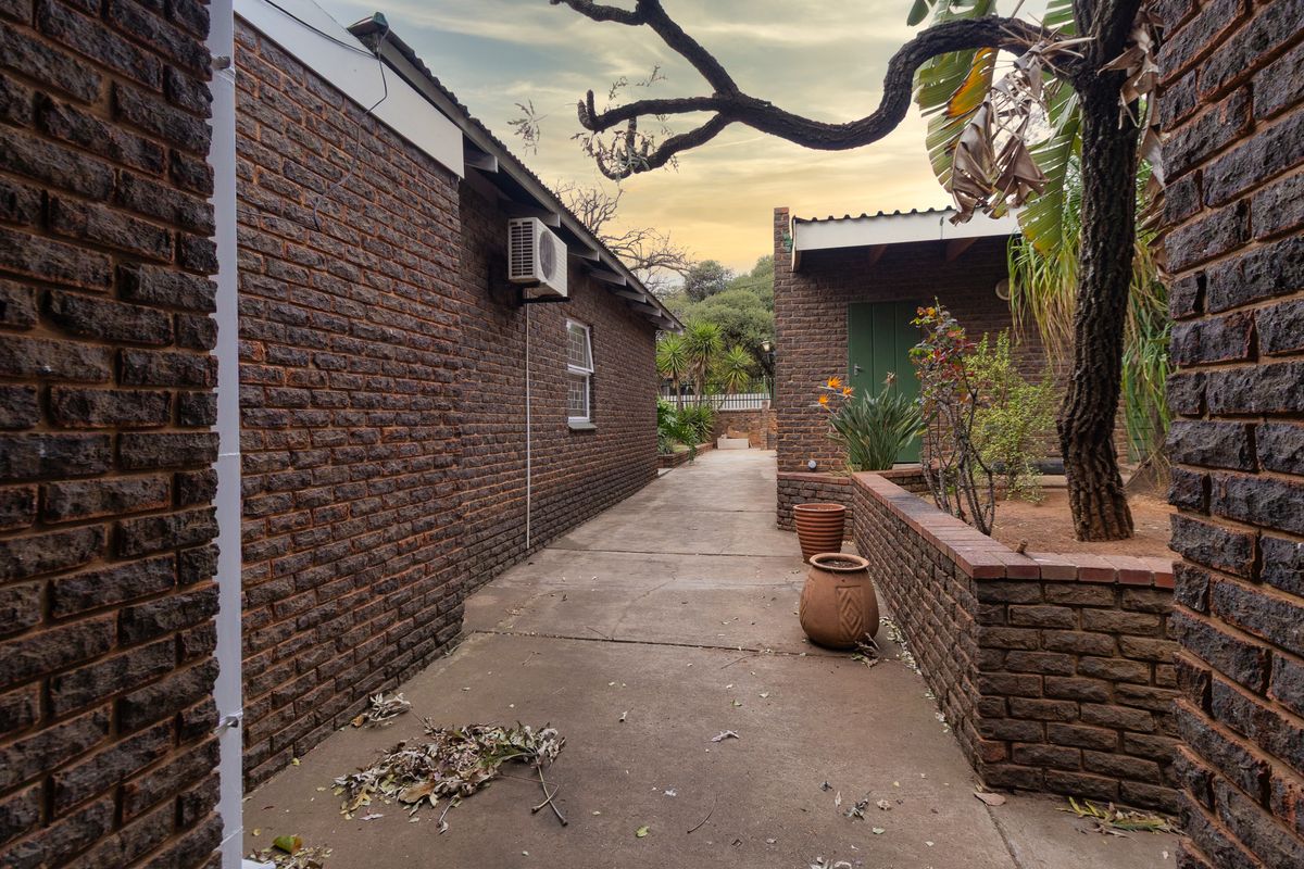 A side walkway featuring face brick walls, a concrete path, and a raised brick planter area leading towards the rear of the property.