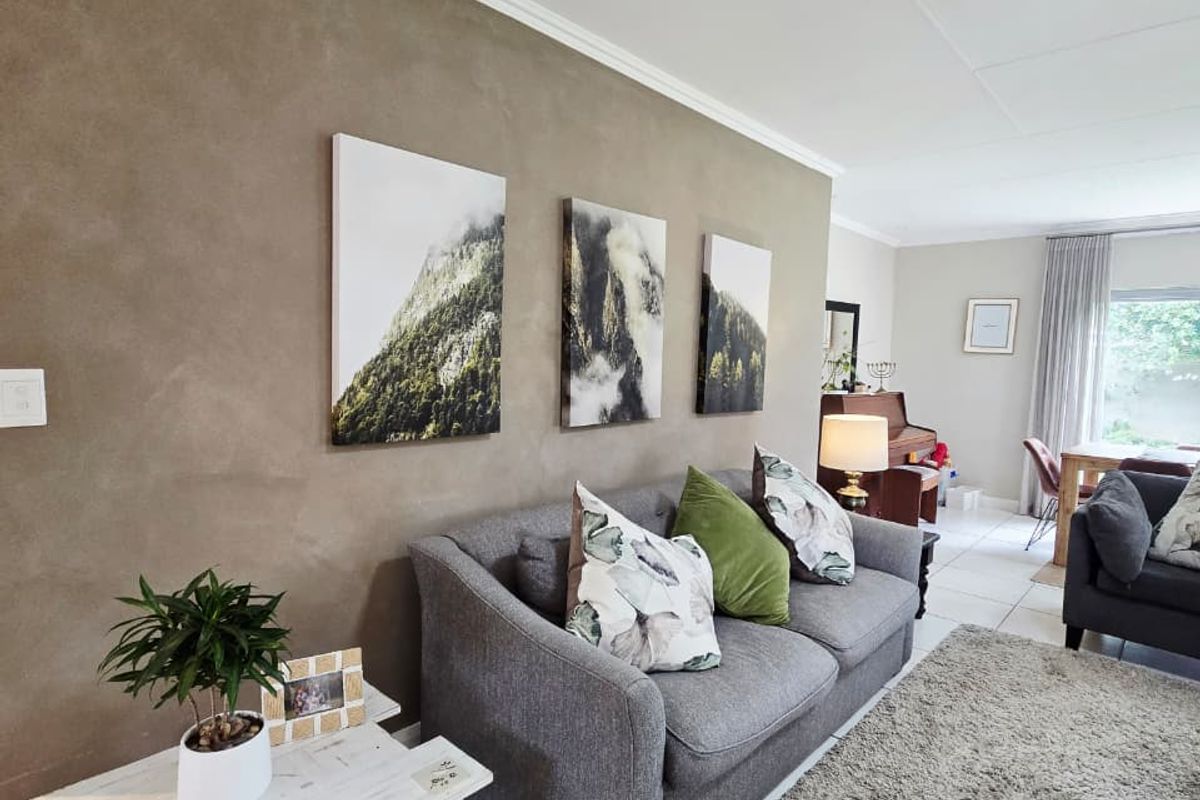 A well-maintained living room featuring neutral tiled flooring, crown molding, and a textured feature wall, creating a comfortable and inviting living space.