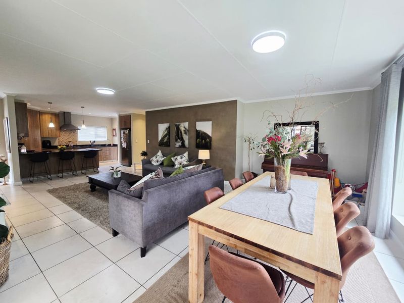 Spacious open-plan living area featuring a modern kitchen with island, dining space, and tiled flooring throughout, creating a functional and cohesive family environment.