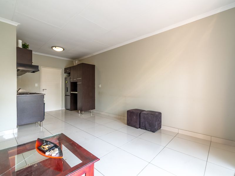 Open plan living area featuring ceramic floor tiles and a compact kitchen with built-in dark cabinetry and an extractor fan.