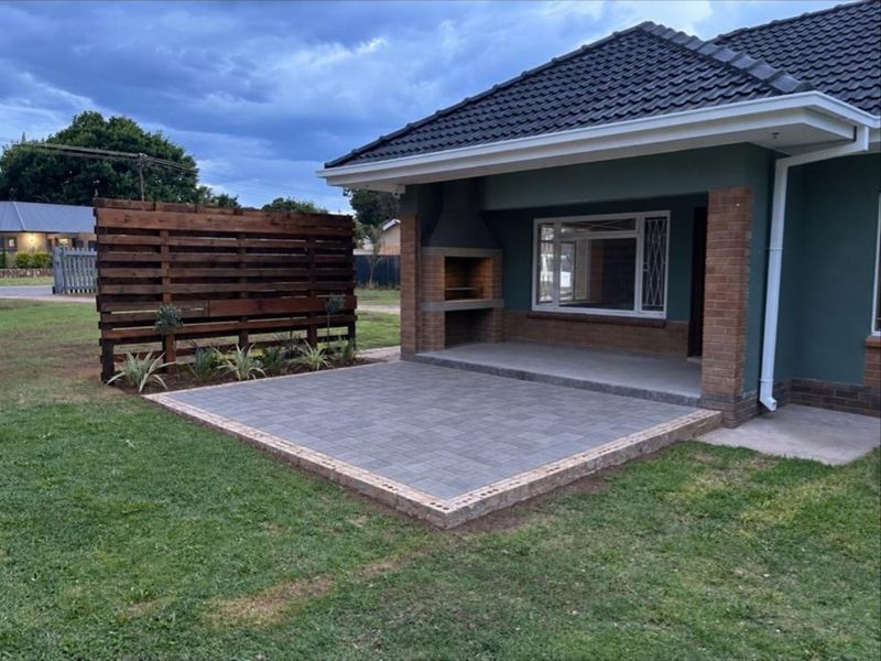 A well-maintained covered patio featuring a built-in braai, paved flooring, and a timber privacy screen, perfect for outdoor entertaining.
