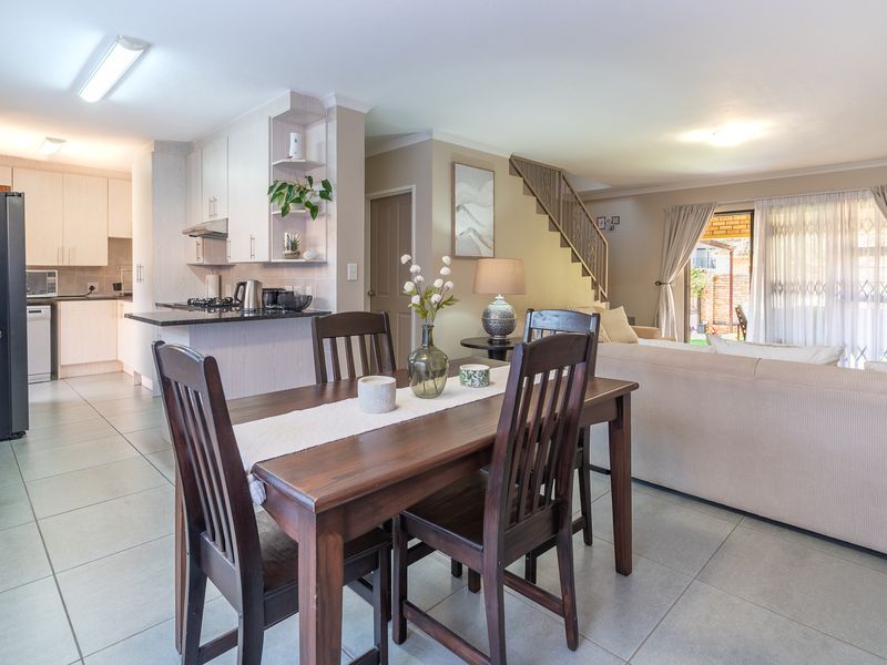 Open-plan living and dining area featuring tiled floors, a functional kitchen with built-in cabinetry, and direct access to the rear patio via sliding doors.