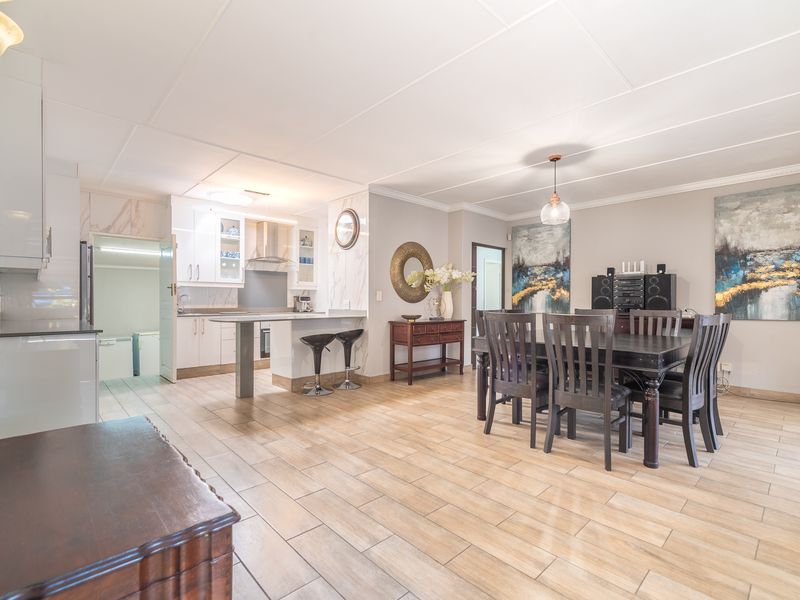 Spacious open-plan living and dining area featuring modern kitchen cabinetry, a central island, and neutral tiled flooring throughout.